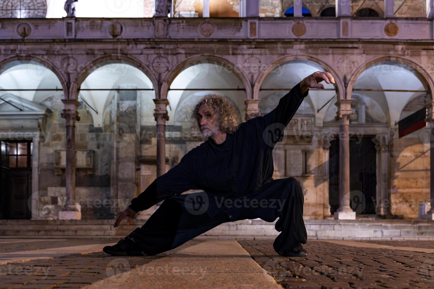 middle aged tai chi master showing stick exercises outdoors amidst the architecture of a medieval cathedral photo