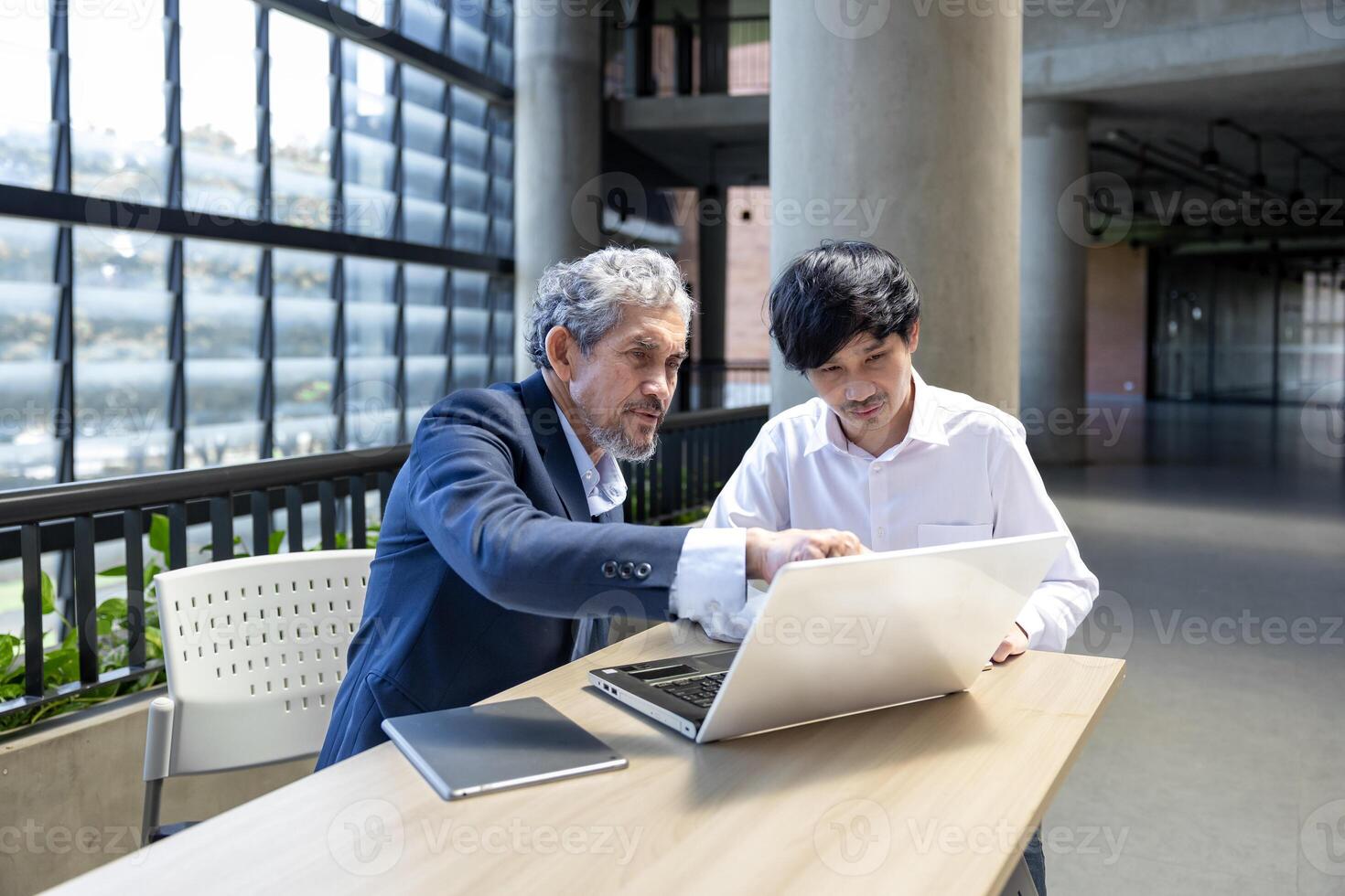 Asian elder professor is giving advice to the college student on the research thesis while sitting in the university faculty for education, academic and business concept photo