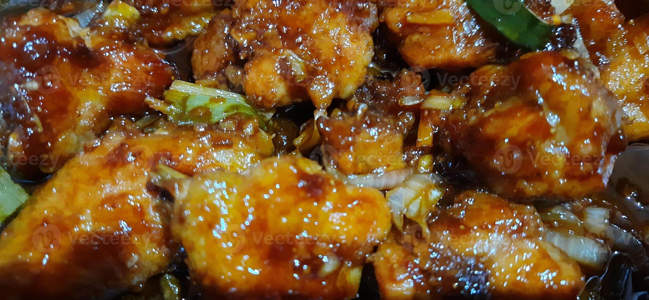 Fried chicken butter or Ayam goreng mentega is fried chicken in buttery sweet soy sauce on the wok pan photo