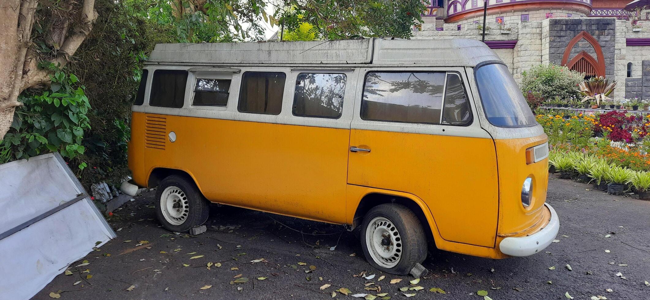 A yellow minibus classic VolksWagen VW camper van parked in the street. Bandung, West Java, Indonesia - October 28 2024 photo