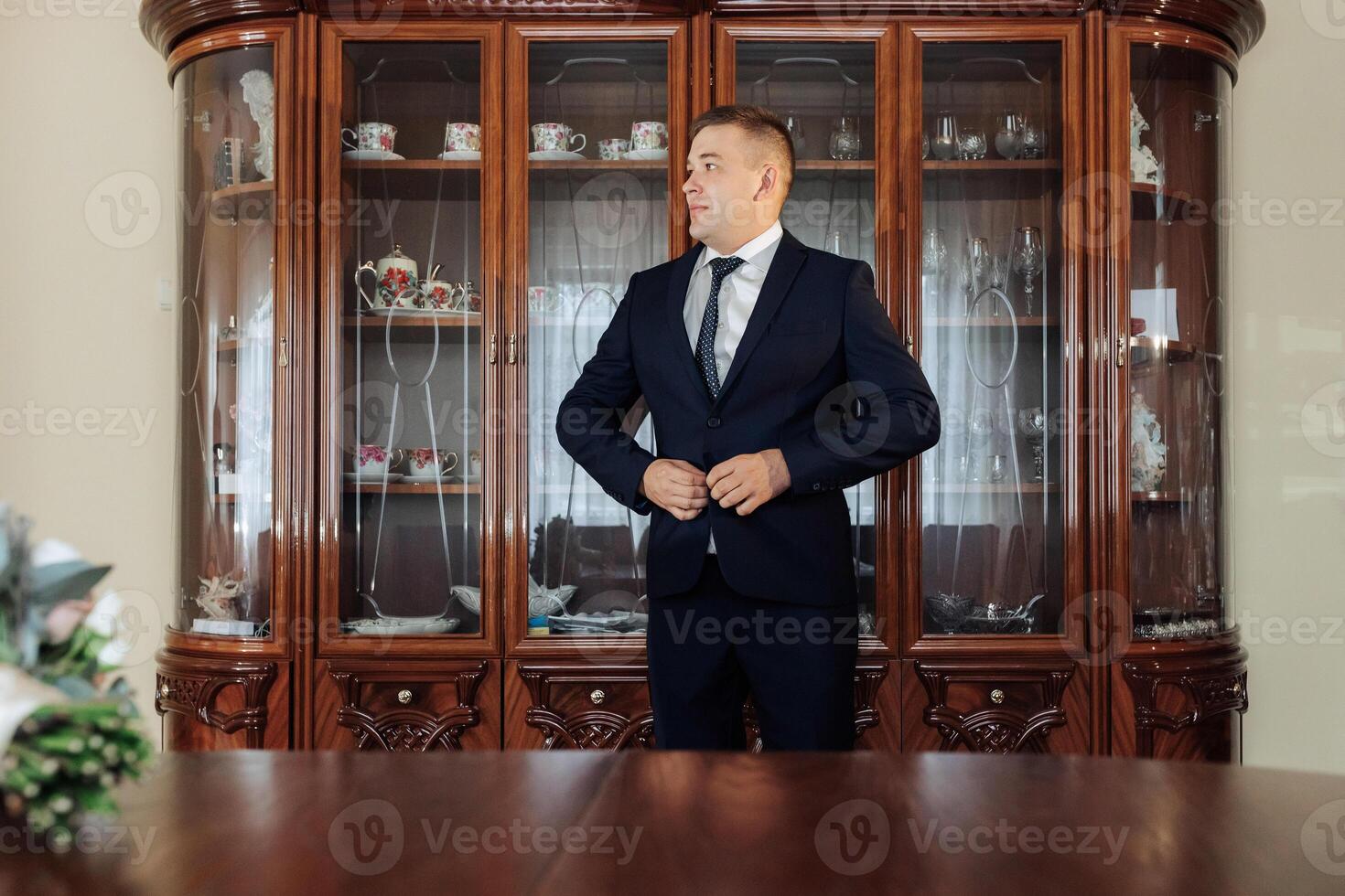 A man in a suit is standing in front of a large wooden cabinet photo