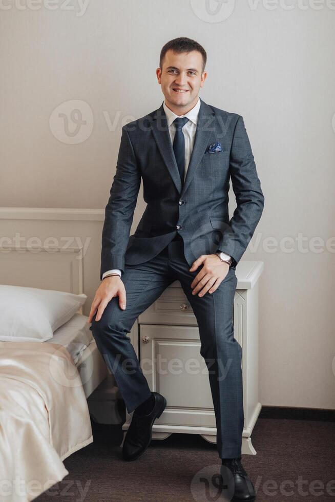 A man in a suit is sitting on a bed photo
