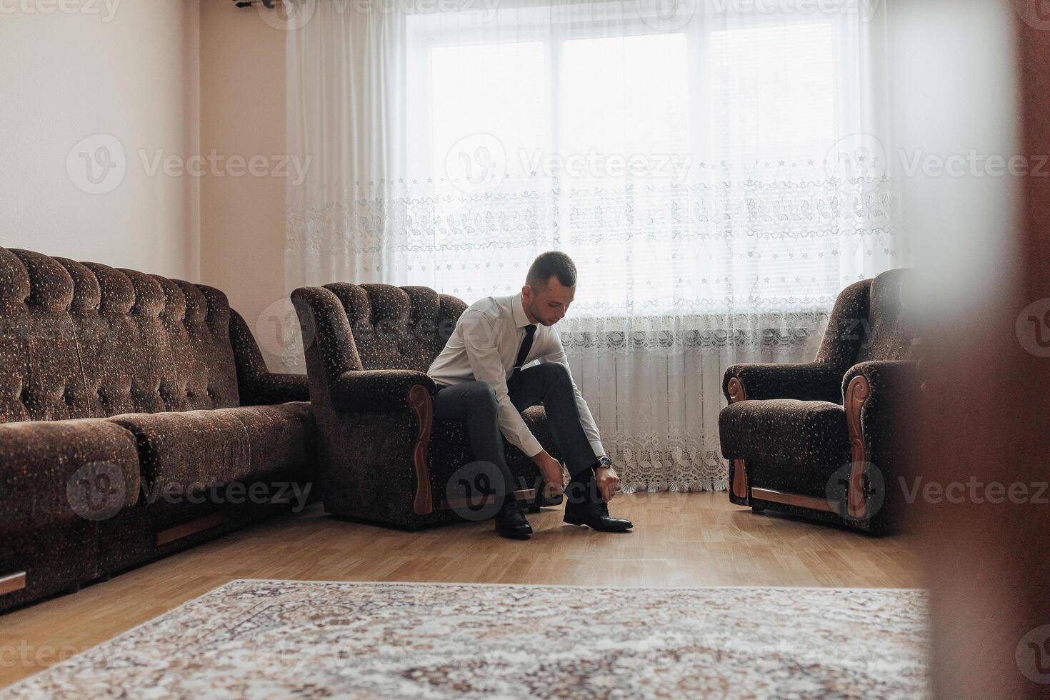 A man is getting ready for a formal event, putting on his shoes photo