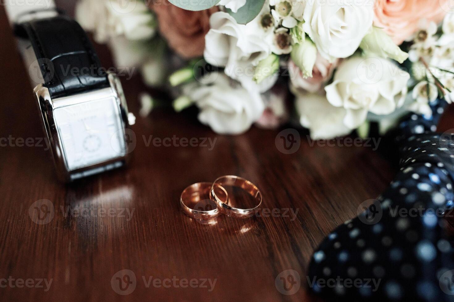 A watch and two rings are on a table photo