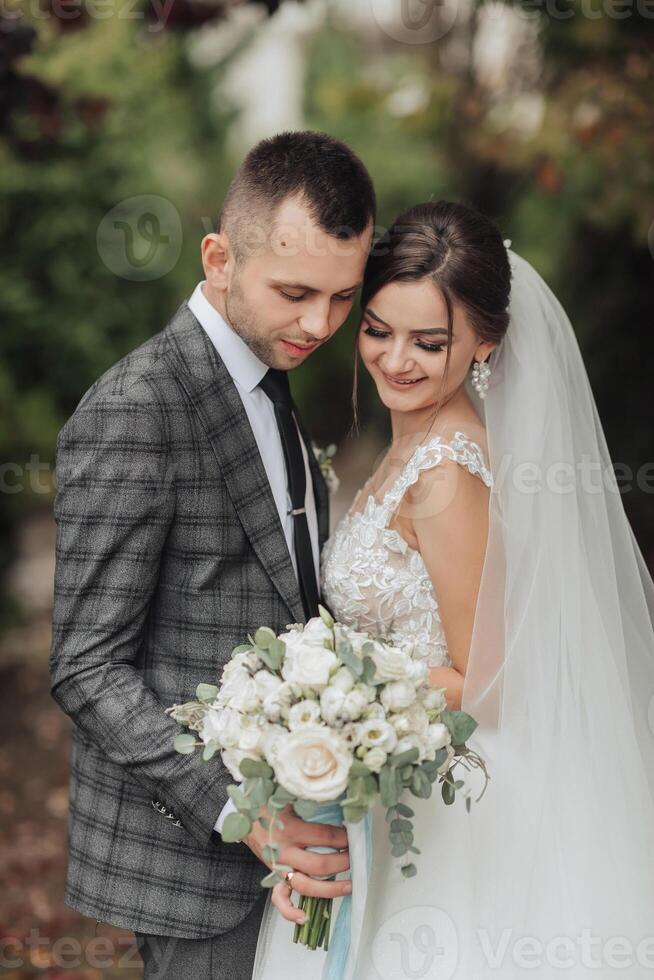 A bride and groom are posing for a picture with a bouquet of flowers photo