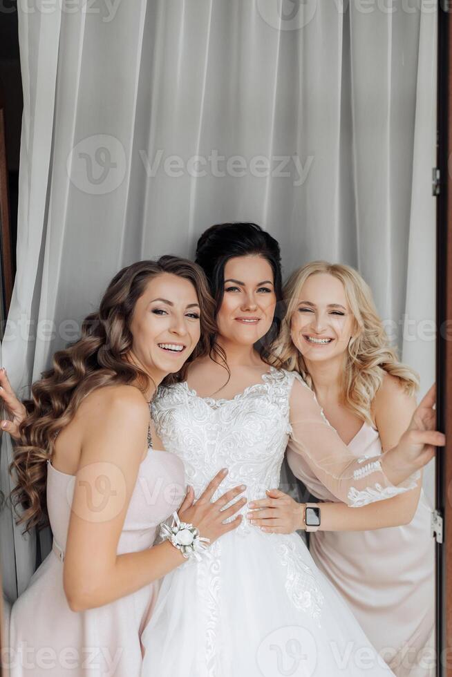 Three women are posing for a picture, with one of them wearing a wedding dress photo