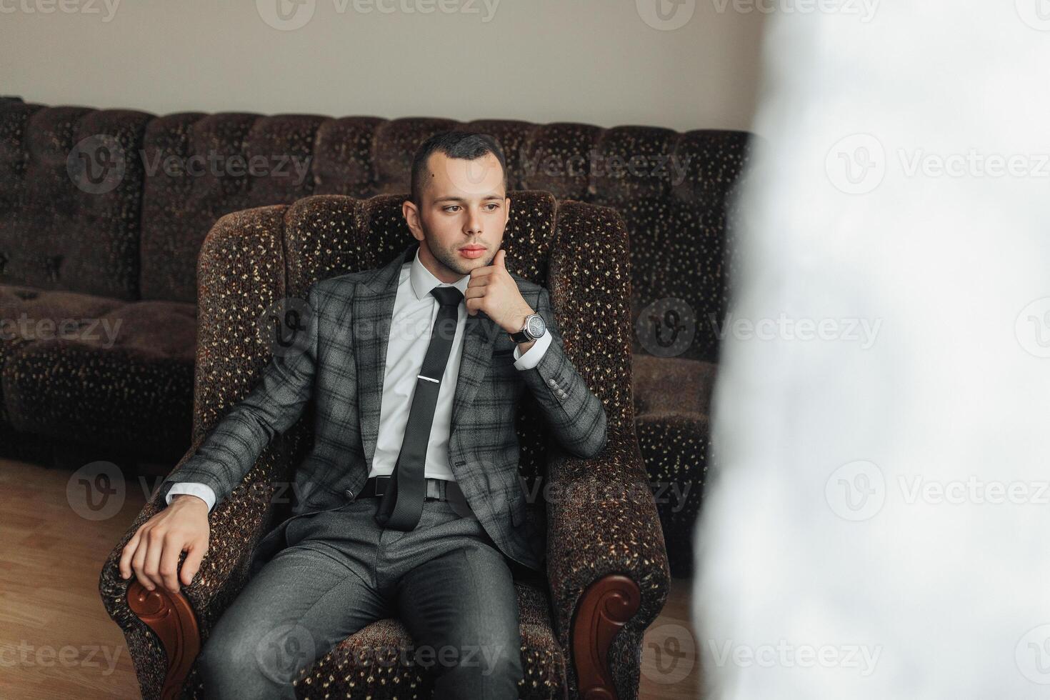 A man in a suit and tie is sitting in a chair photo