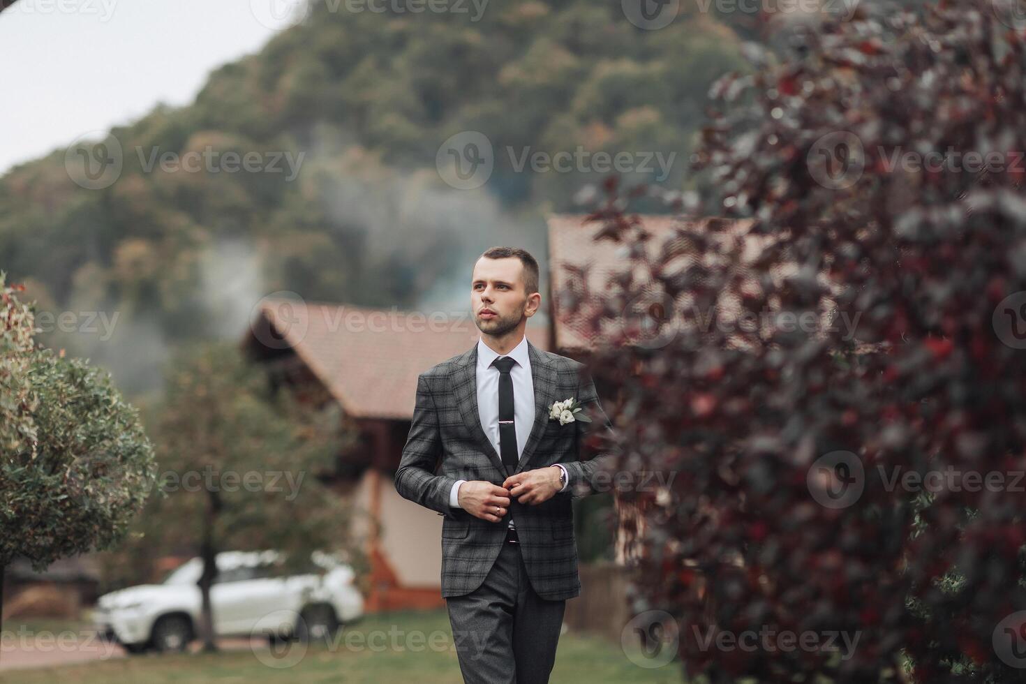 A man in a suit and tie is walking through a forest photo