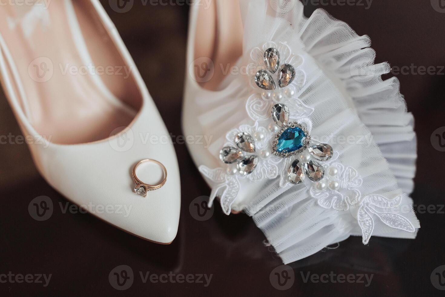 A white shoe with a blue stone on it and a ring on the left foot photo