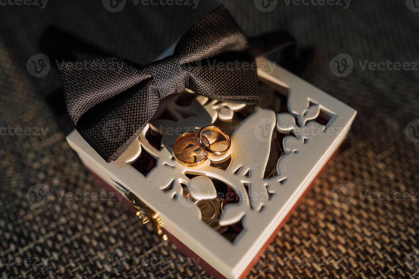 A box with a bow on it and two rings inside photo