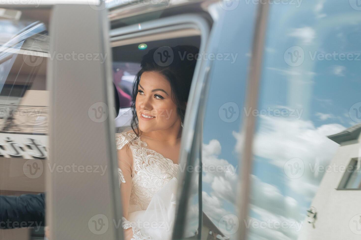 A woman in a wedding dress is getting into a limousine photo
