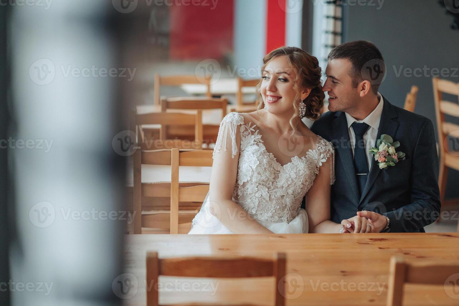 A bride and groom are sitting at a table in a restaurant photo