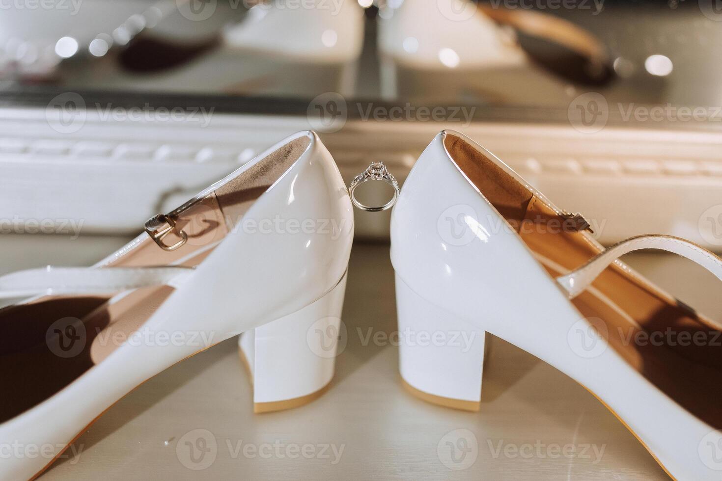 Two white shoes with a ring on the left one photo