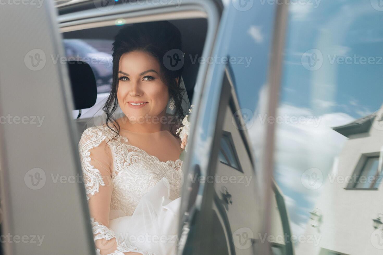 A woman in a wedding dress is sitting in the back of a limousine photo