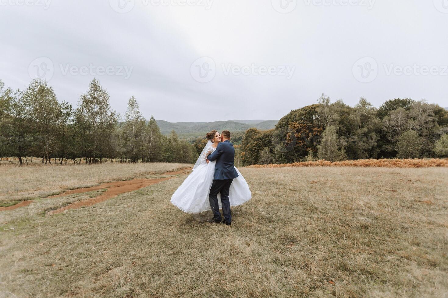 A bride and groom are standing in a field photo