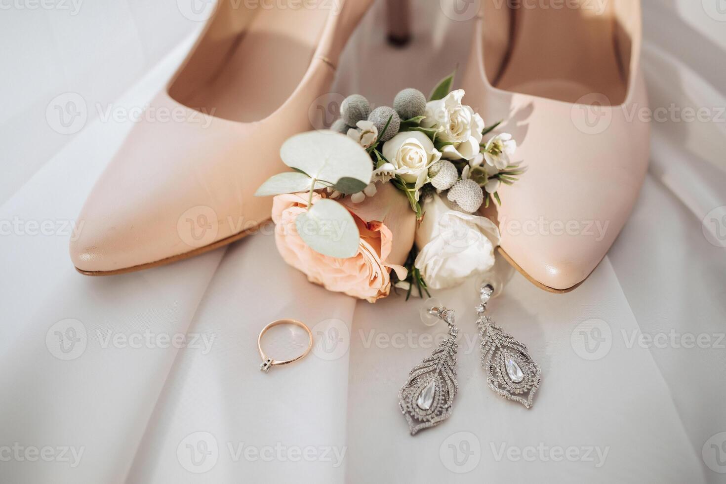 A pair of high heels with a flower on top and a ring on the left foot photo
