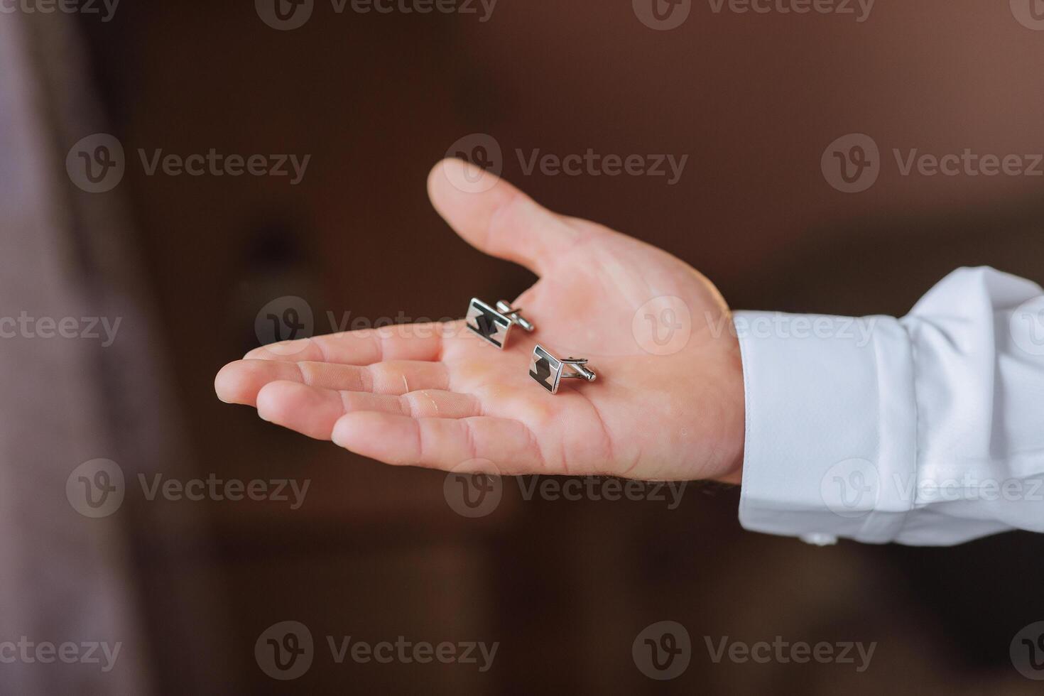 A hand holding two cufflinks photo