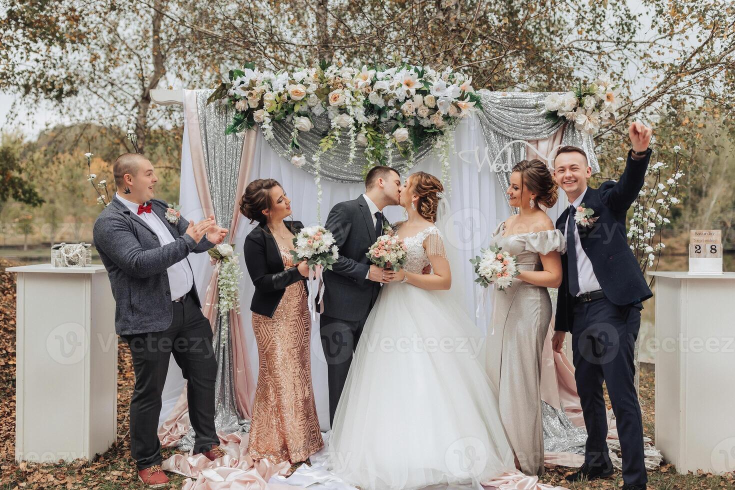 A group of people are posing for a picture in front of a wedding arch photo
