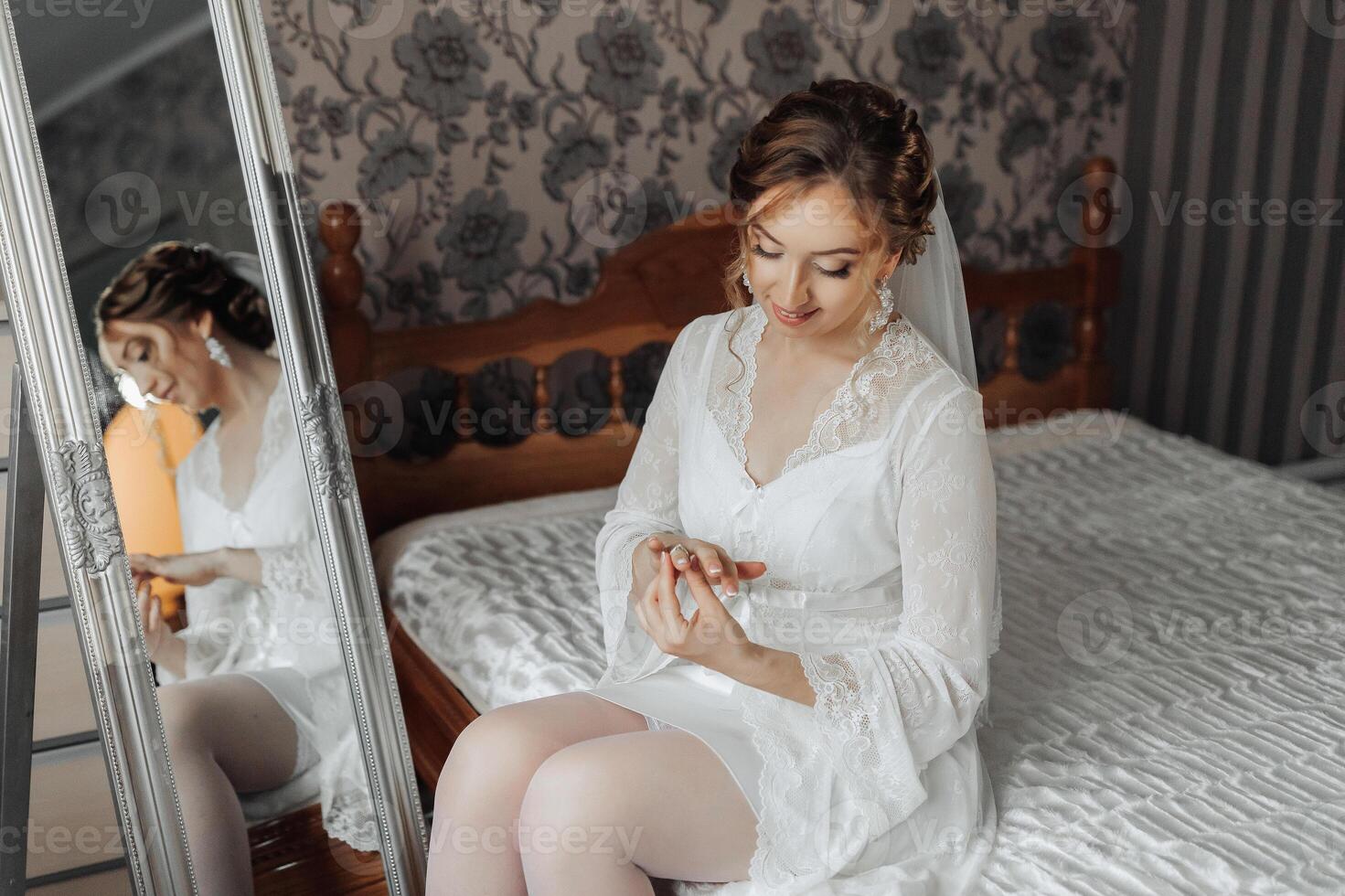A woman is sitting on a bed and looking at her reflection in a mirror photo