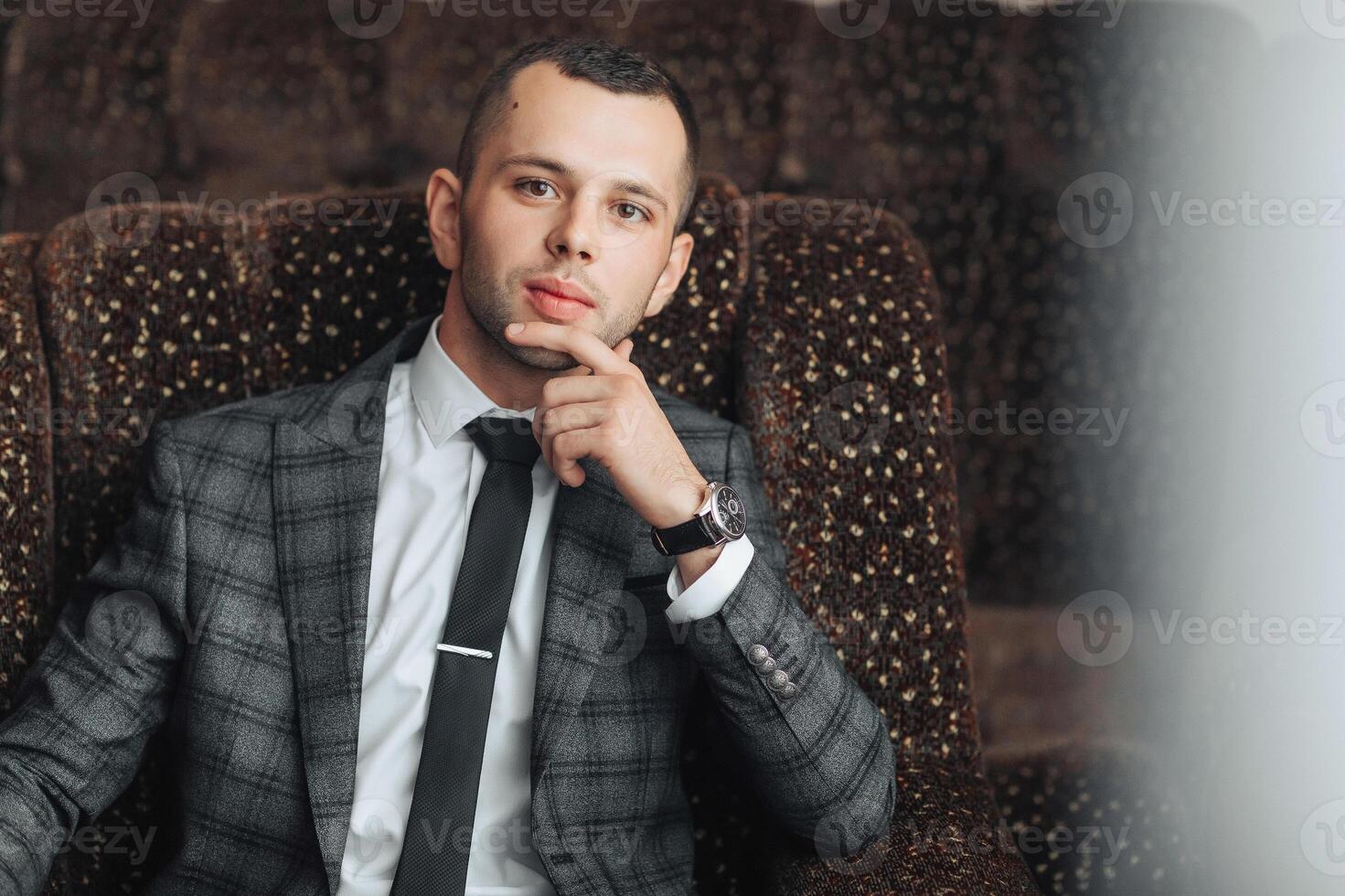 A man in a suit and tie is sitting in a chair photo