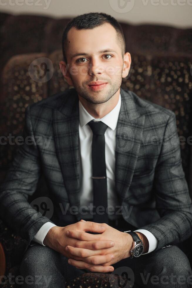 A man in a suit and tie sits on a couch photo