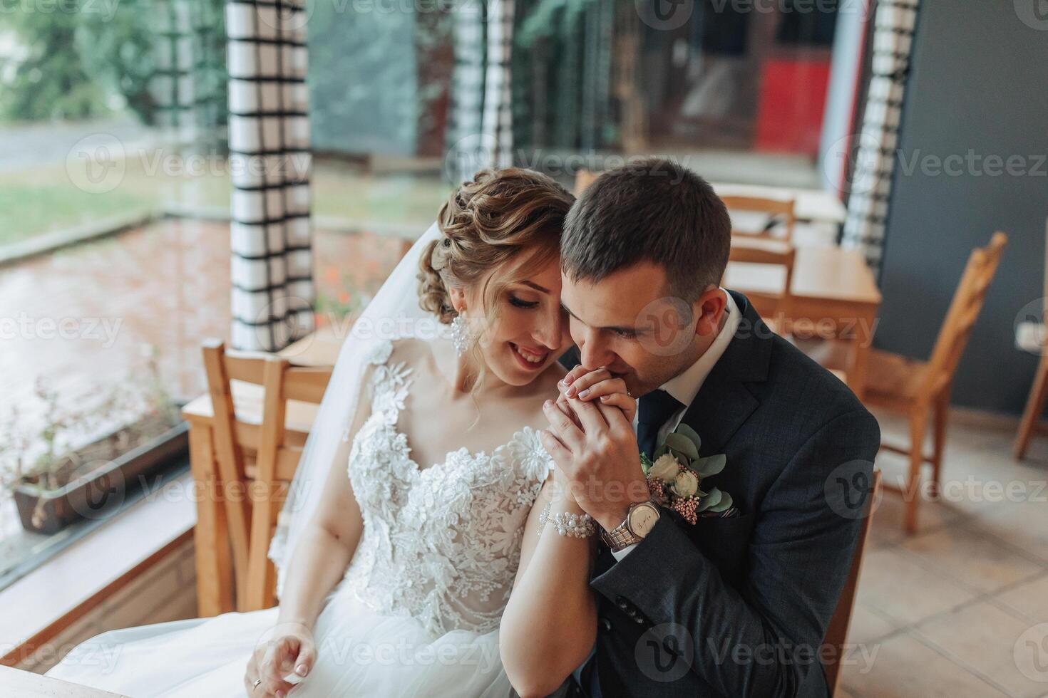 A bride and groom are sitting at a table in a restaurant, holding hands photo