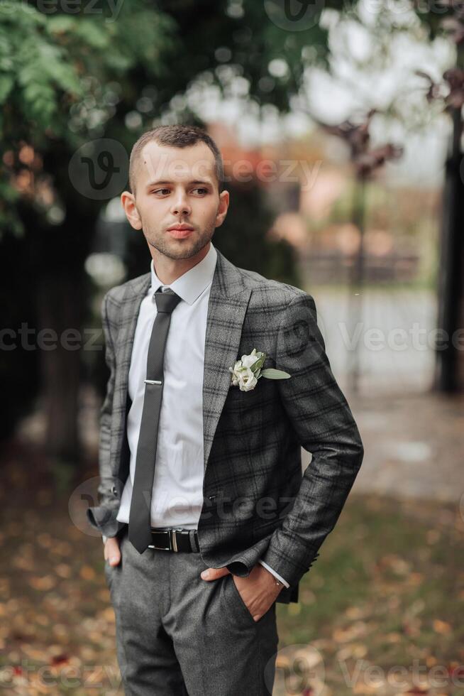 A man in a suit and tie stands in a field with a flower in his lapel photo