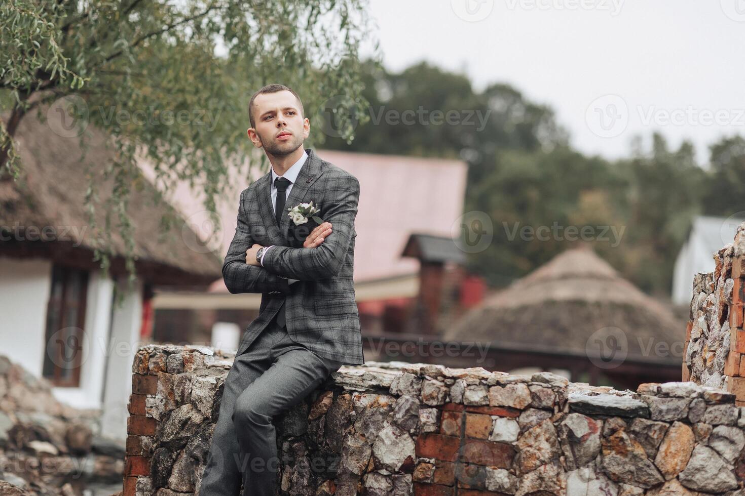 A man in a suit is sitting on a stone wall photo
