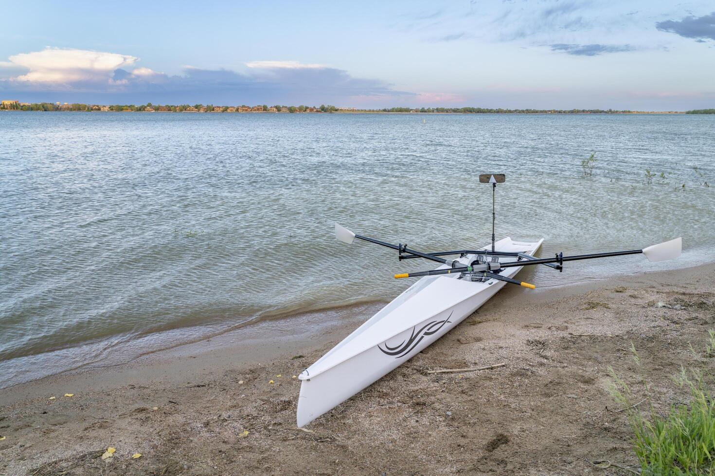 Loveland, CO, USA - June 2, 2024, Rowing shell by Liteboat on a beach at dusk, Boyd Lake State Park in spring scenery. photo