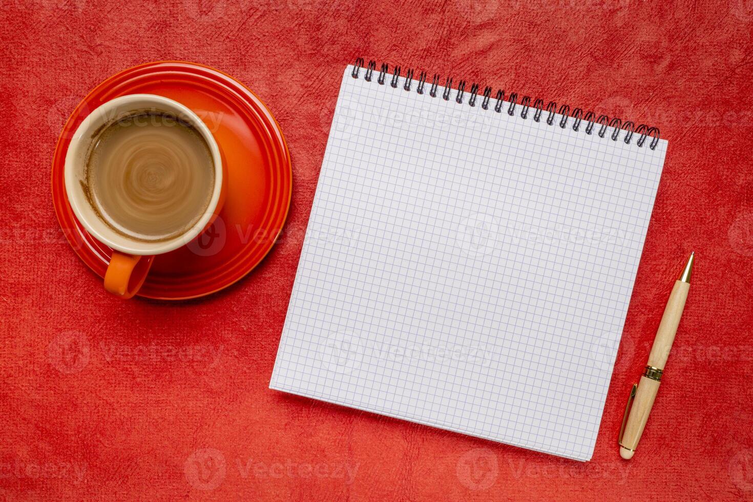 blank spiral notebook with ruled paper, flat lay with coffee on red textured art paper photo