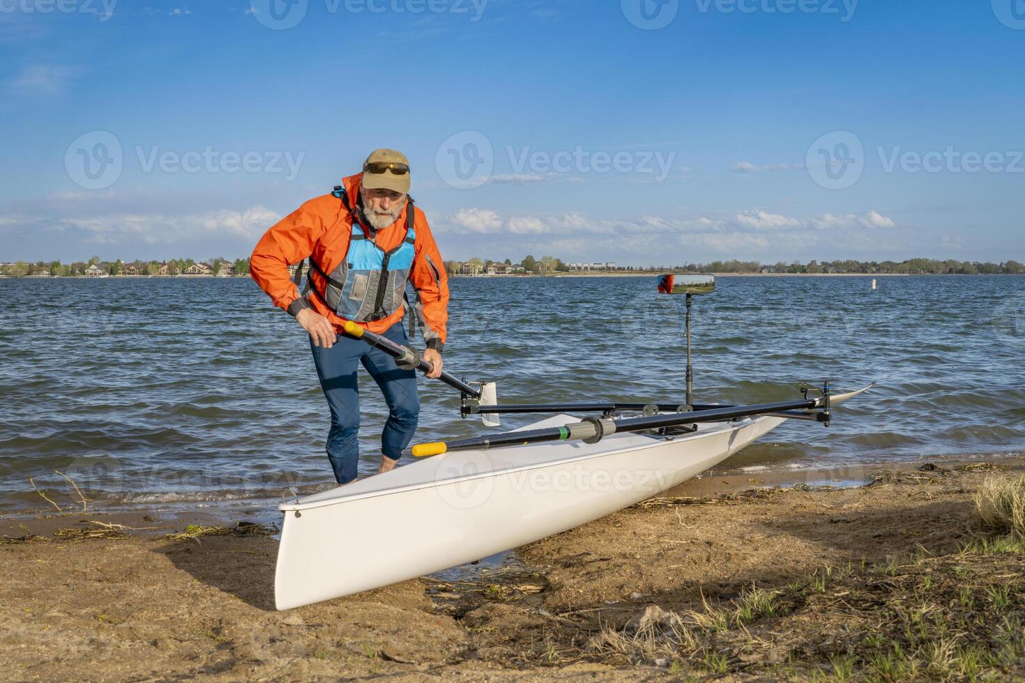 Senior male rower with his rowing shell on a beach of Boyd Lake in northern Colorado, early spring scenery photo