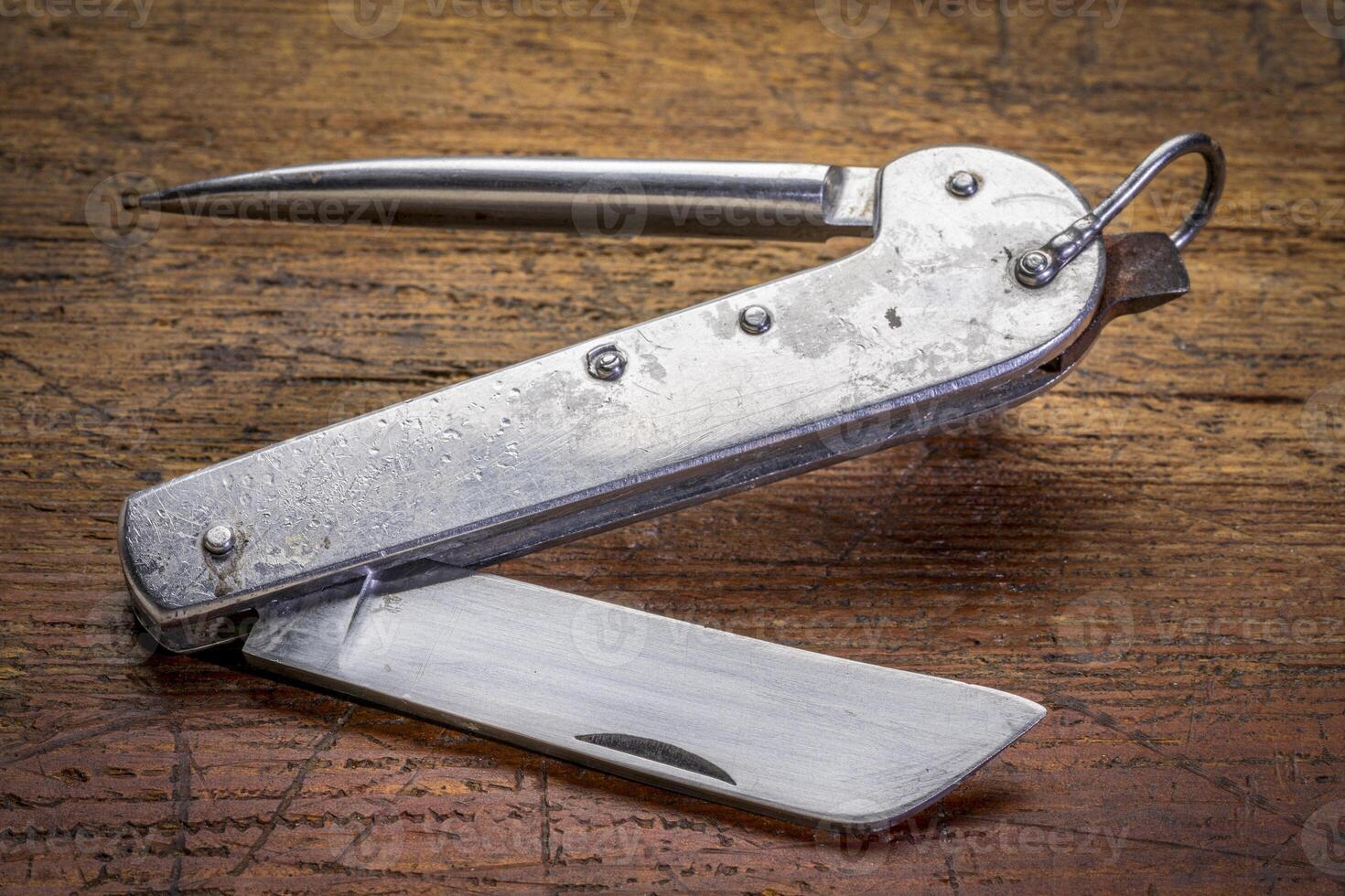 vintage sailor knife with marlinespike and straight blade, made in Poland in 1970s, against rustic wood, signs of heavy use and abuse photo