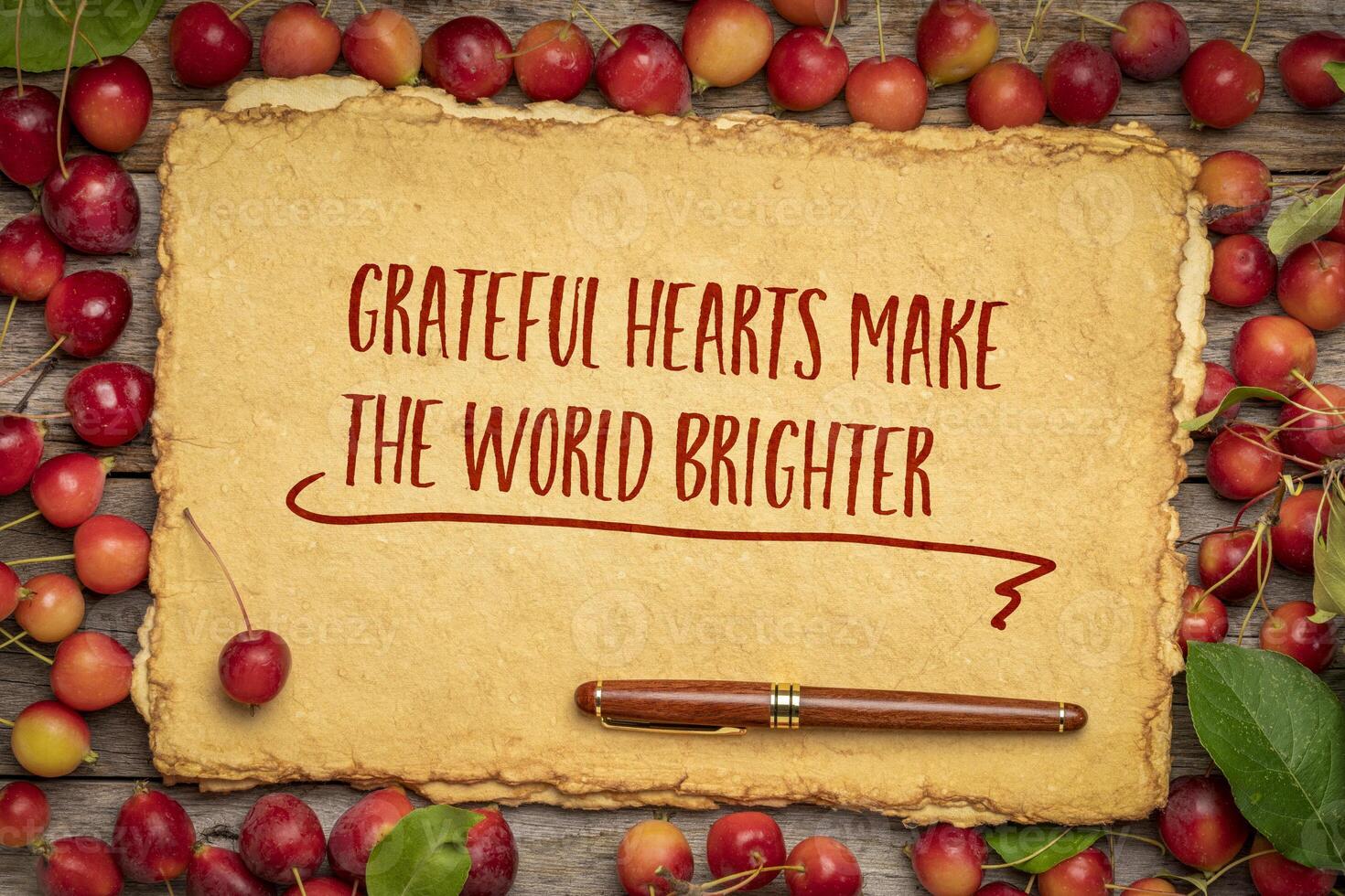 Grateful hearts make the world brighter - Thanksgiving inspirational slogan, handwriting on a handmade paper framed by red crab apples photo