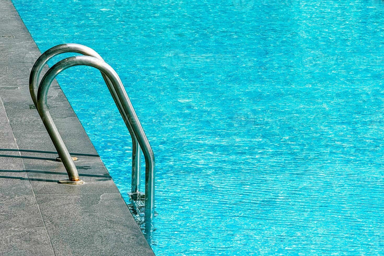 Serene pool with a stainless steel ladder invites relaxation at a summer resort photo