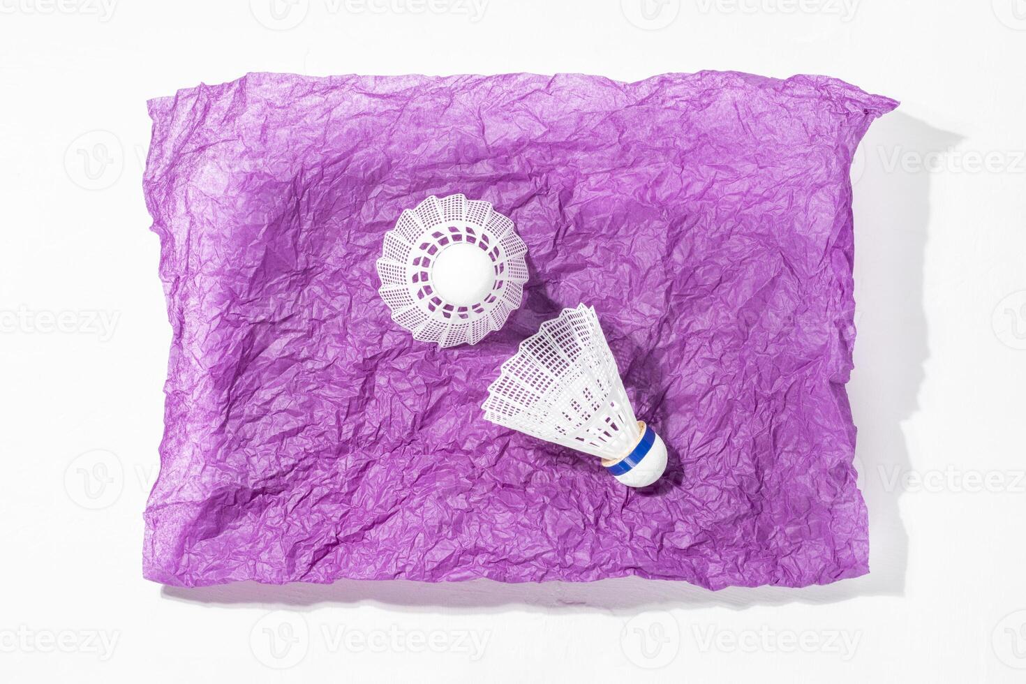 Sport composition with two badminton shuttlecocks on crumpled purple paper photo