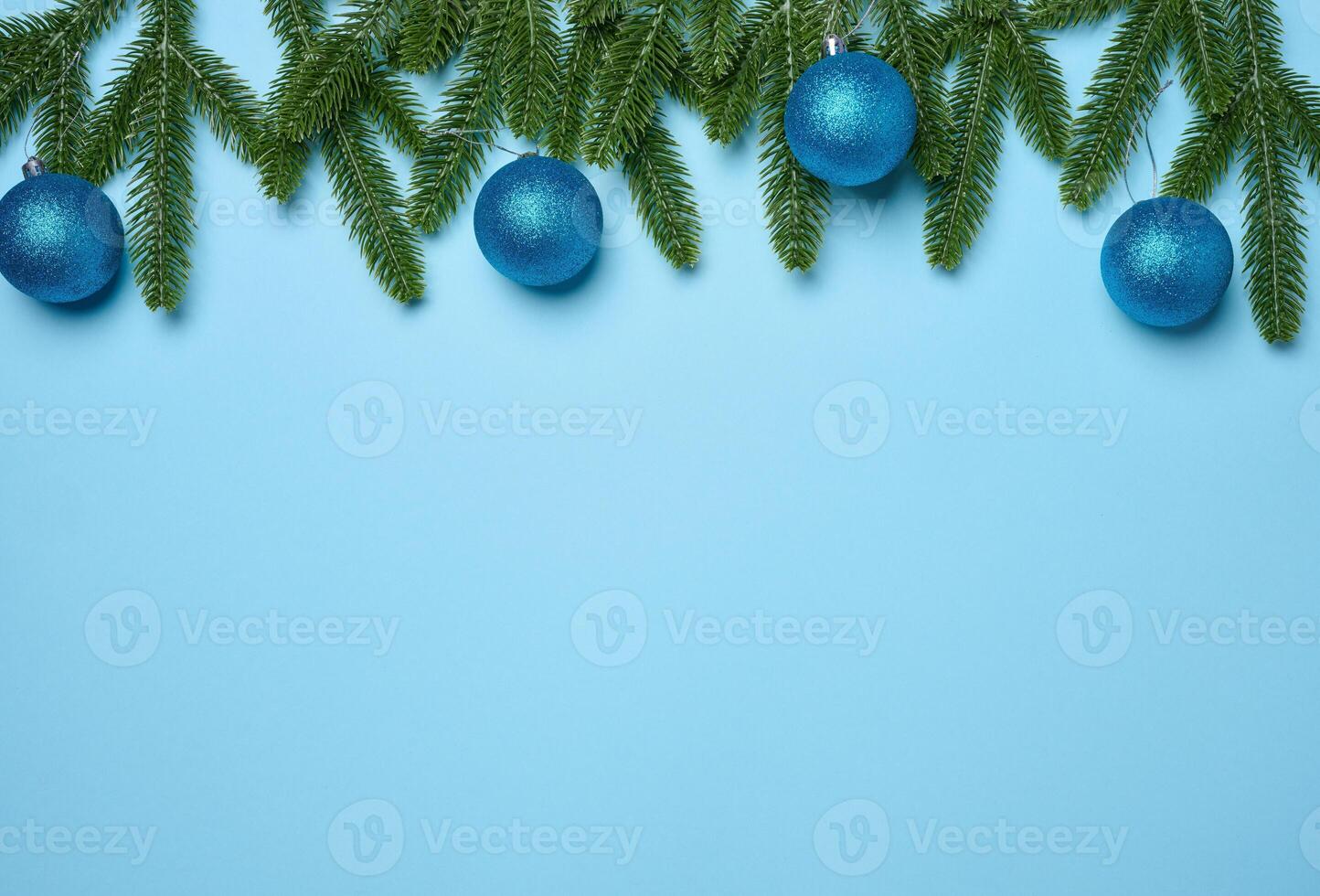 Shiny blue balls and green fir branches on green background, Christmas background. photo