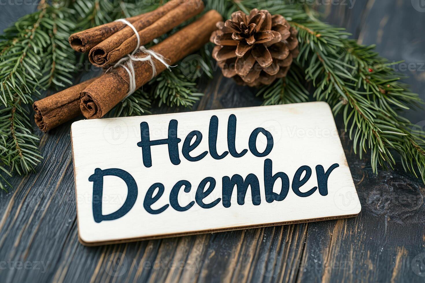 Hello December sign with cinnamon sticks and pinecone on wood photo