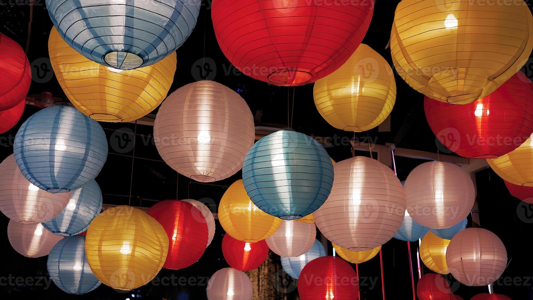 Colorful Various illuminated paper lanterns lights hanging in dark background at Thai Red Cross Fair night market, carnival season photo