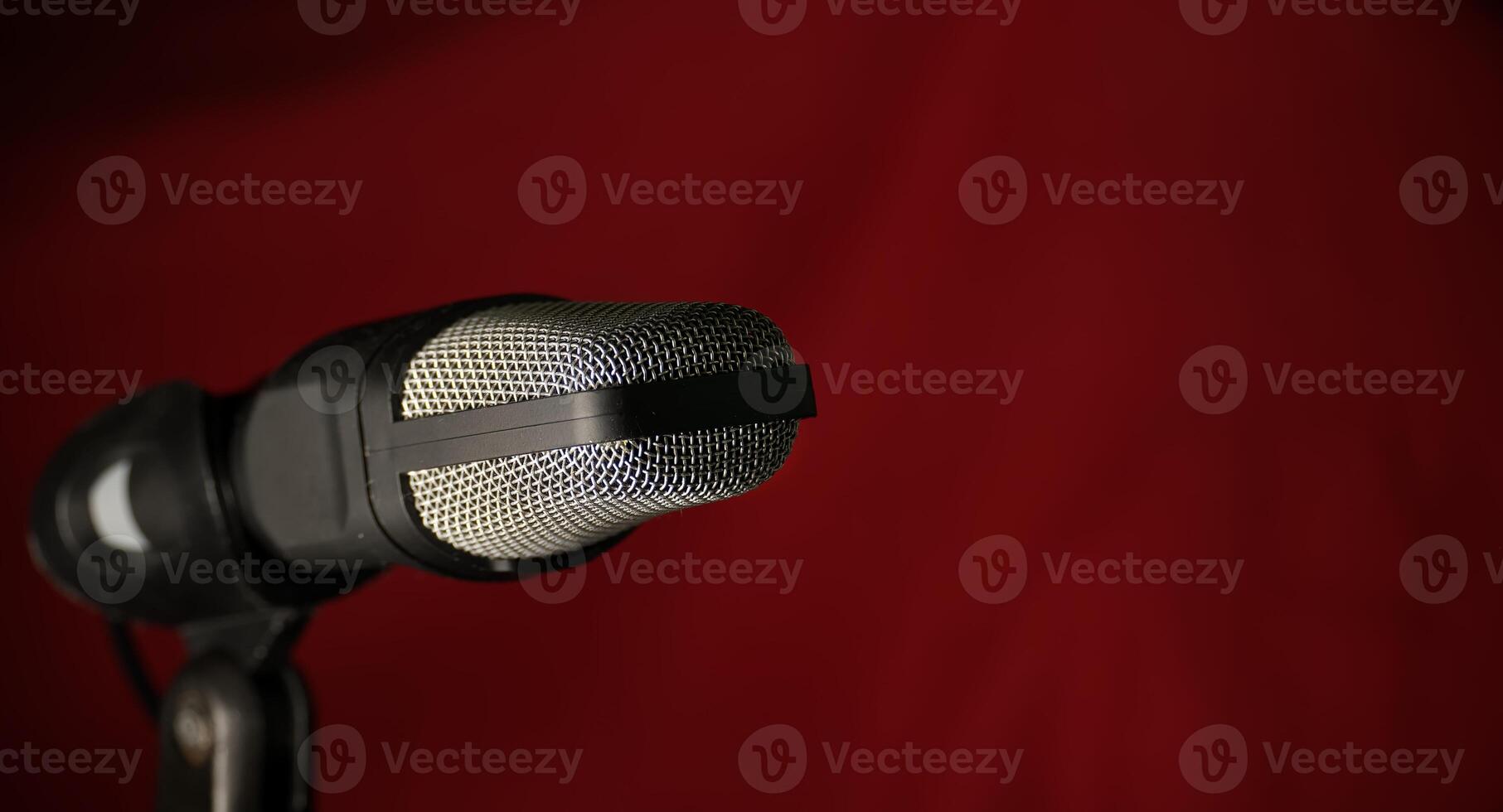 Professional studio microphone with metal mesh grille against dark red background photo