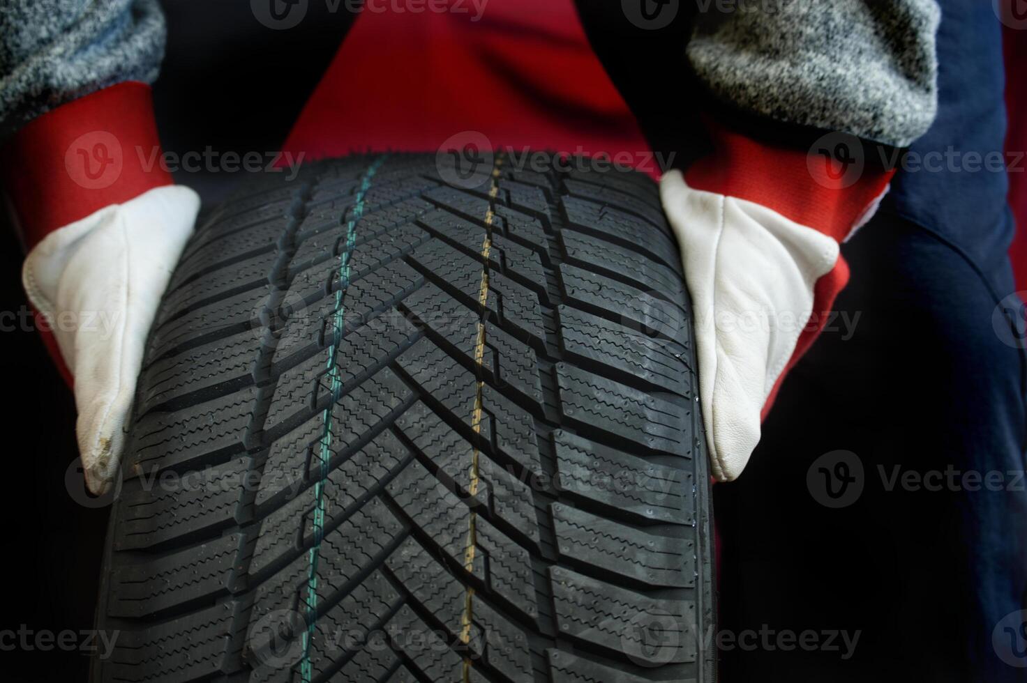 Mechanic wearing protective gloves inspecting a heavy-duty tire in a workshop setting photo