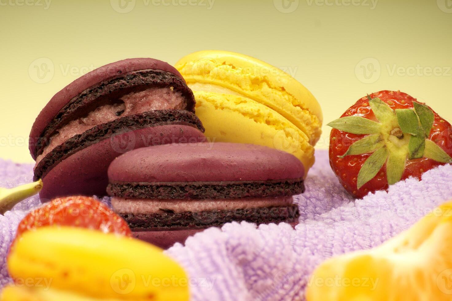 Assortment of macaroons and fruits on purple cloth photo