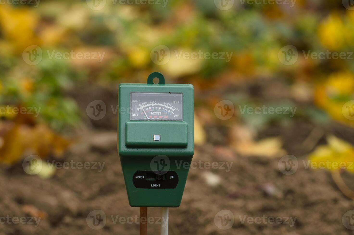 Close-up of a soil moisture and pH meter in a garden setting to monitor plant care conditions photo