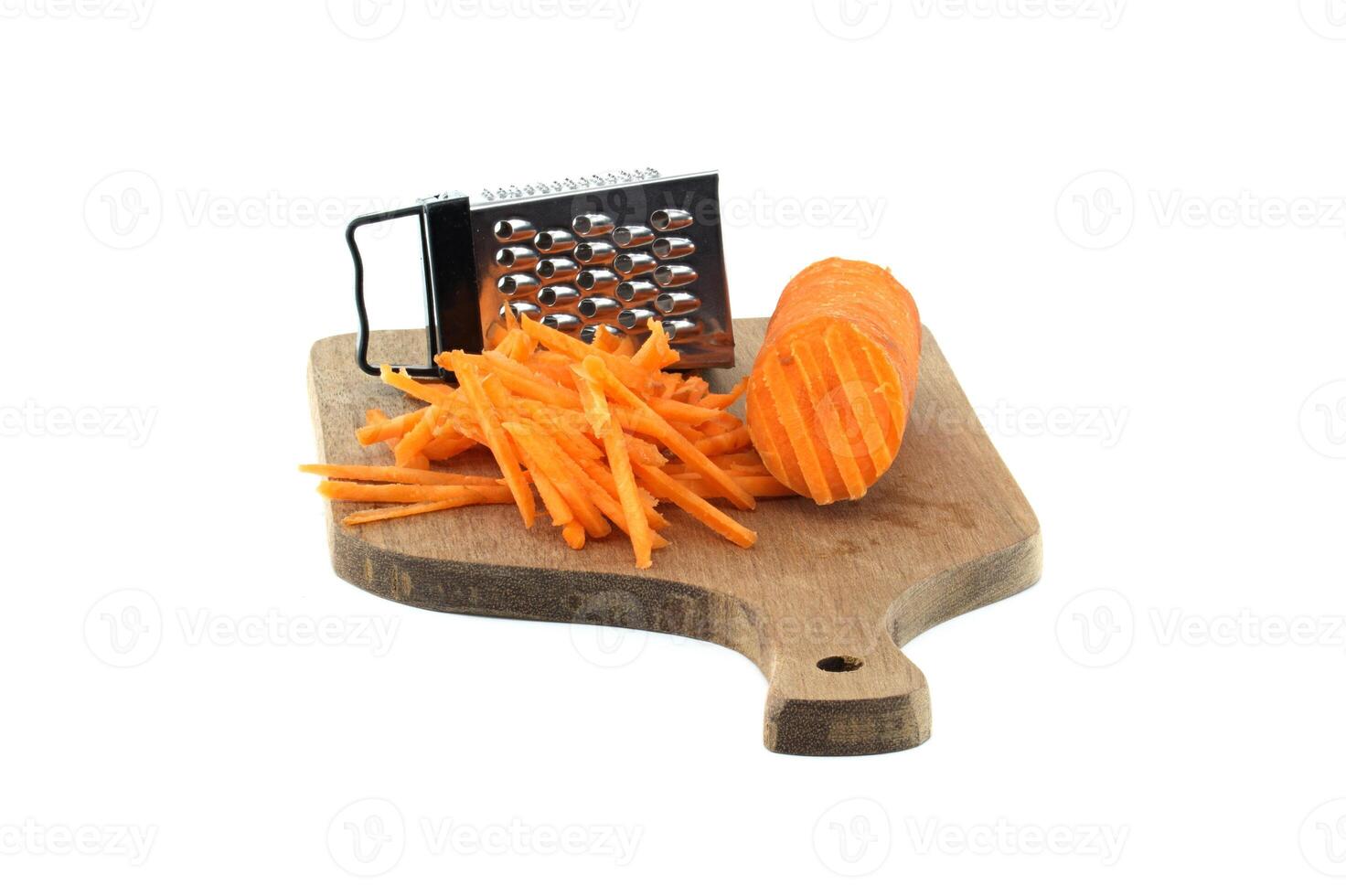 Grated carrots on a wooden cutting board with a metal grater isolated on white background photo