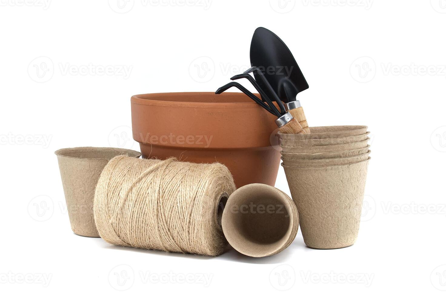 Gardening tools with terracotta pot, biodegradable pots, and spool of twine on a white background photo