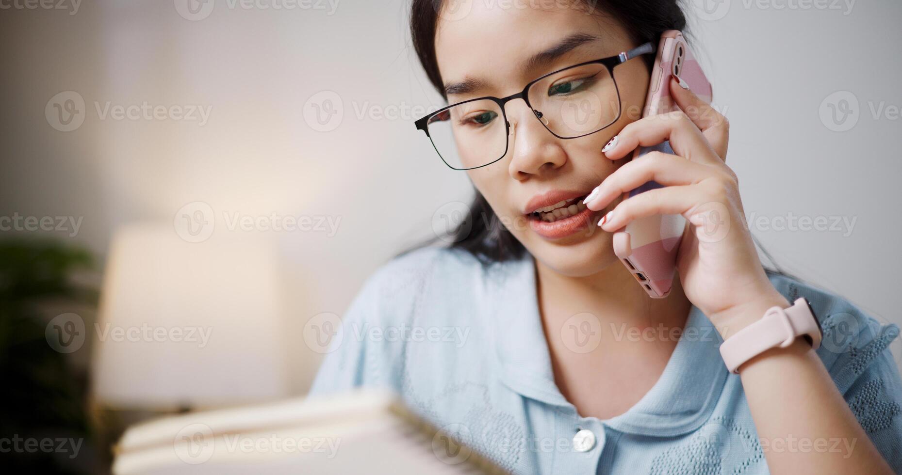 Selective focus, Female freelancer sitting at desk explain work to co-workers via mobile phone in home office. photo