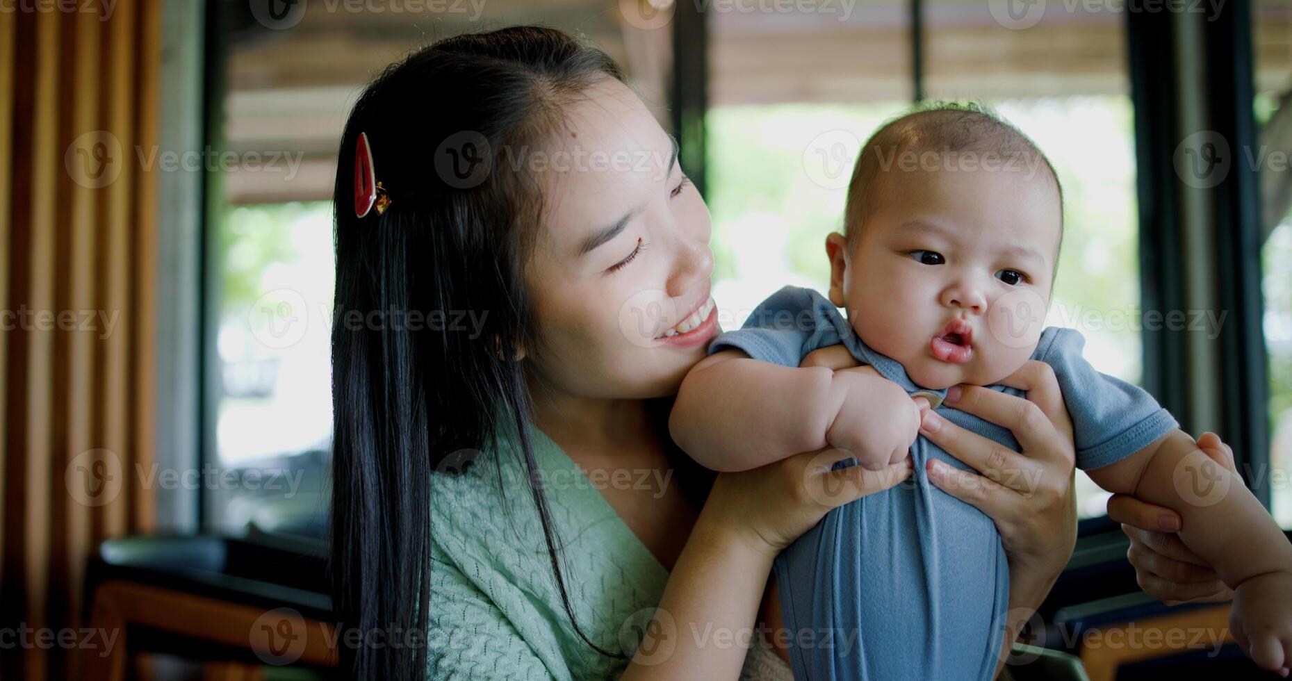 Selective focus, Happy moment in a coffee shop as two women smile and play with a baby boy. Family enjoying time together. photo