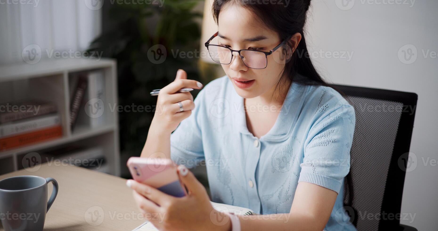 High angle view, Female freelancer sitting at desk call explain work to coworkers via mobile phone in home office. photo