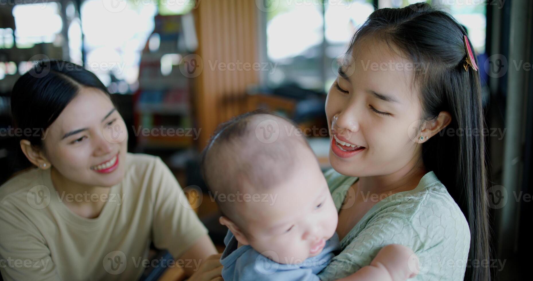 Selective focus, Two happy women having fun playing with a little boy in a coffee shop. Family enjoying time together. Happy lifestyle. photo