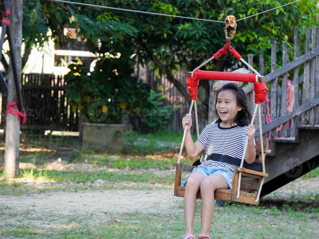 Kids play outdoors on a playground with modern slides, rope net bridges, climbing swings, climbers in summer. photo