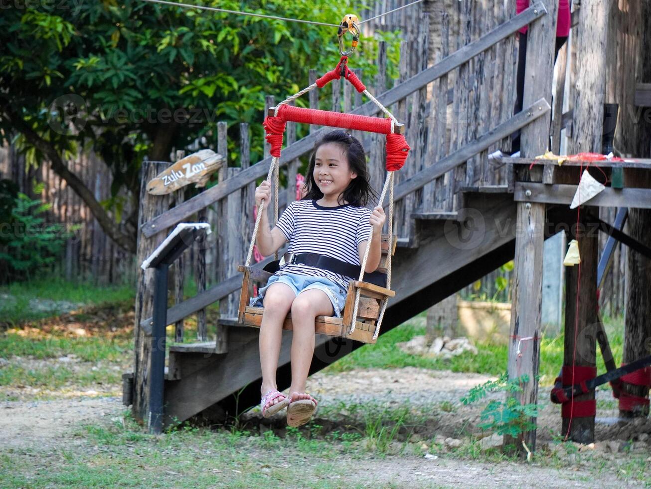Kids play outdoors on a playground with modern slides, rope net bridges, climbing swings, climbers in summer. photo